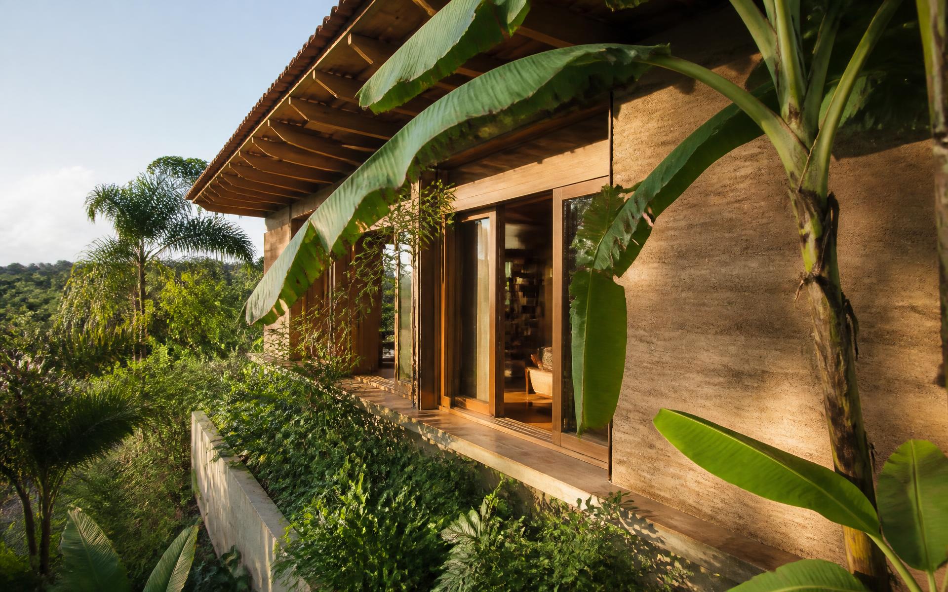 Casa de arquitetura sustentável com beirais largos integrada à vegetação tropical